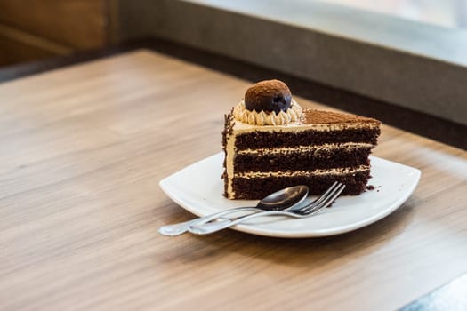 one piece of chocolate cake with chocolate ball toping on wooden table,shallow focus