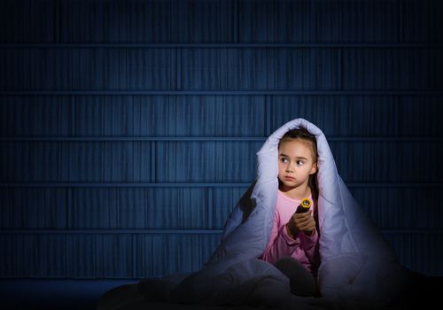 girl under the covers with a flashlight