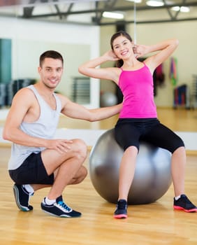 male trainer with woman doing crunches on the ball