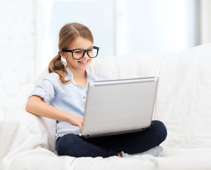smiling girl in specs with laptop computer at home