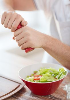 close up of male hands flavouring salad in a bowl