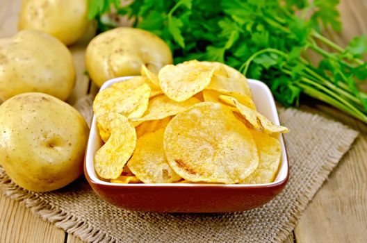 Chips in bowl with potatoes on sacking and board
