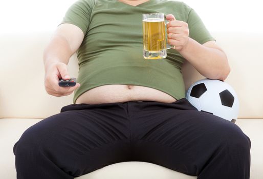 fat man drinking beer  and sitting on sofa to watch TV