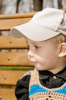 Portrait of little boy in cap outdoors.