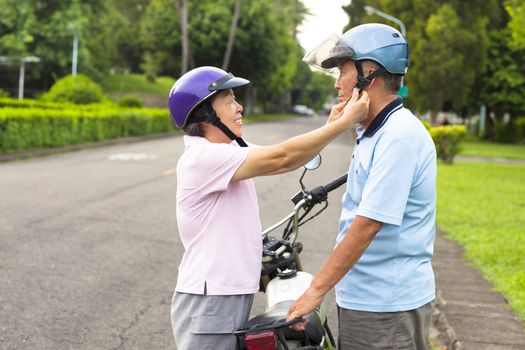 happy grandmother help grandfather to wear a helmet