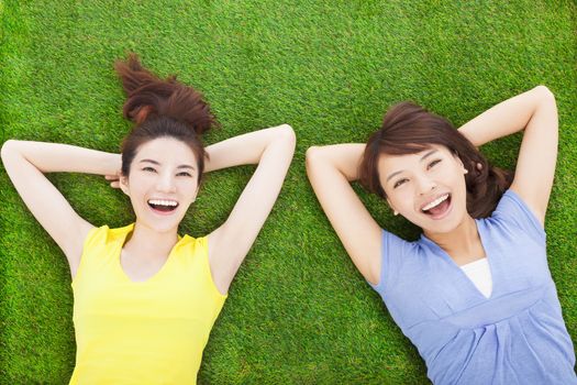two smiling  young woman lying  on meadow