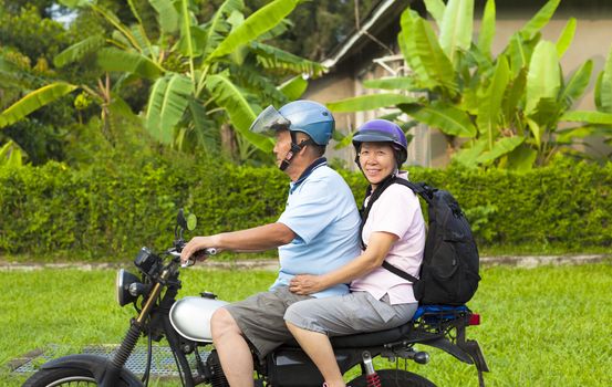 asian senior couple driving motorcycle to travel