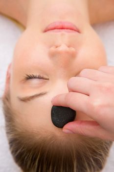 Therapist placing stone woman's forehead