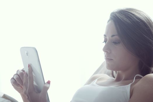 Woman using digital tablet in bed 
