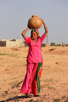 Local woman carrying jar with water on her head, Khichan village