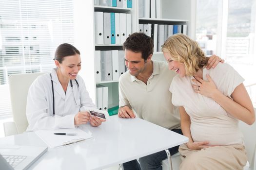 Gynaecologist and expectant couple looking at reports
