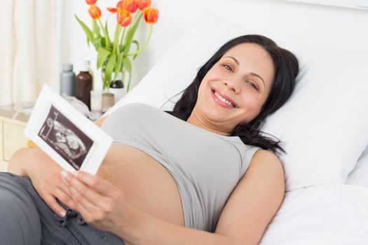 Smiling pregnant woman holding sonography report