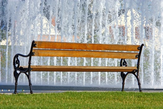 Empty wooden bench in the park in front of the fountain
