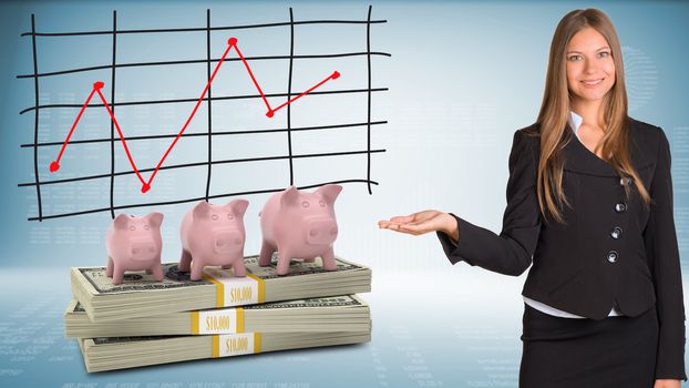 Businesswoman points hand on piggy banks and money
