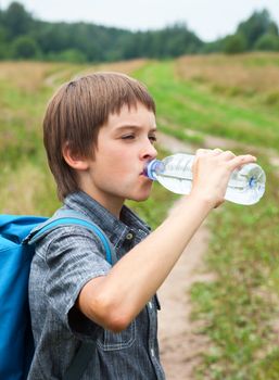 Boy drinking water from pet bottle outdoors