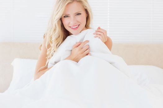 Sexy blonde covering herself with duvet