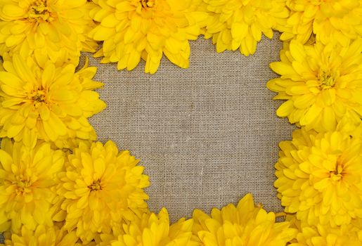 Frame of yellow flowers against a background of rough cloth