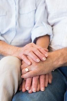 Retired couple holding hands at home in living room