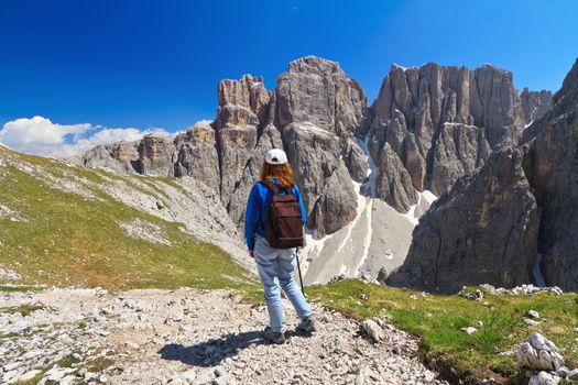 hiker on footpath  in Sella mountain, on background Mezdi valley and Piz da Lech peak, south Tyrol, Italy