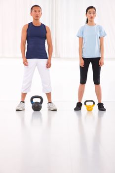 Asian man and woman doing kettle bell crossfit exercise