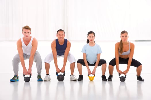 Multiethnic group of people doing kettlebell crossfit exercise