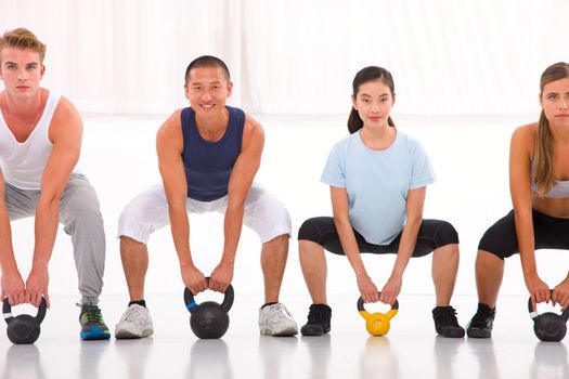 Multiethnic group of people doing kettlebell crossfit exercise