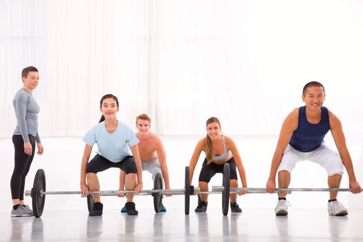 Multiethnic group with weightlifting bar workout in fitness cent