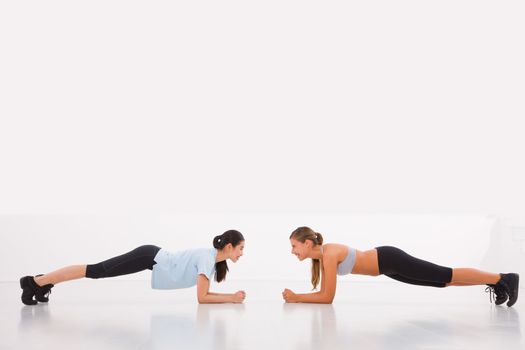 Two young woman doing push-ups in gym
