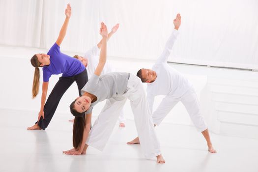 Diverse group of people practicing yoga in fitness studio