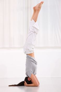 Young woman doing yoga headstand pose