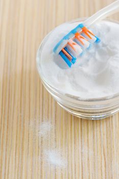  sodium bicarbonate and a toothbrush  on a wooden surface