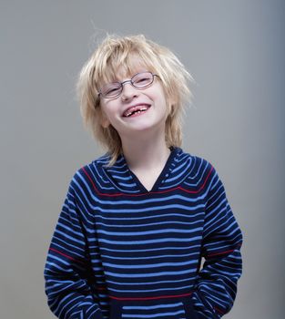 portrait of a boy with glasses showing his first missing milk teeth