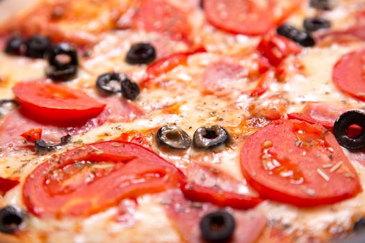 Close-up shot of delicious Italian pizza with ham, tomatoes and 