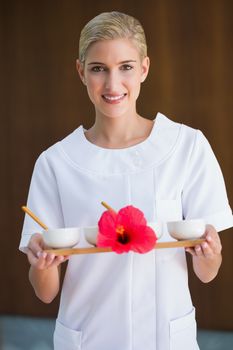Smiling beauty therapist holding tray of treatments at the spa