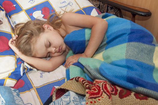 child of four years sleep in a bed with an old sheets and blankets