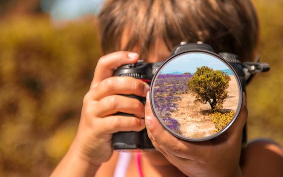 Young girl taking photos of tree in a meadow by professional dig