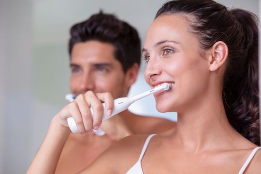 Attractive couple brushing their teeth in the morning at home in bathroom
