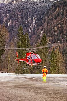 Red helicopter landing at swiss heliport in alps