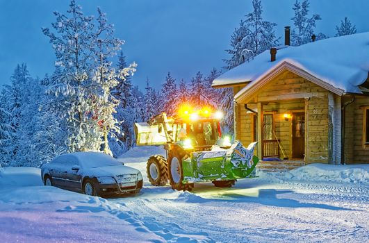 Tractor cleaning snow near house in winter finland 