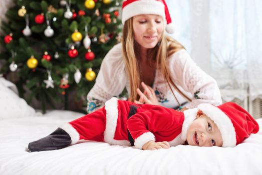 Mother playing with baby dressed in Santa costume
