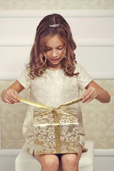 Portrait of luxury little princess with gold gift box