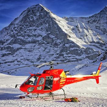 Red helicopter landed near alpine peak near Jungfrau mountain