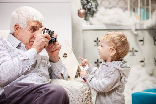 Senior man taking photo of his toddler grandson