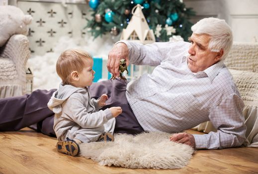 Toddler boy and his grandpa playing with toy