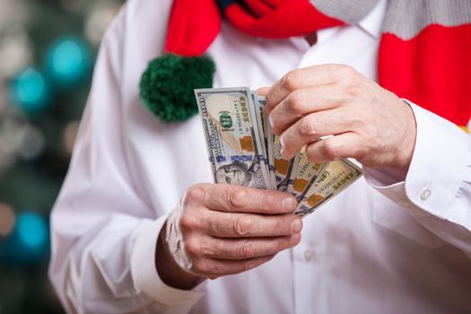 Senior man with money on Christmas background