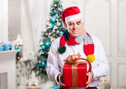 Senior man with gift box on Christmas background