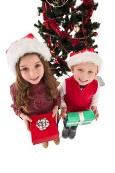 Festive little siblings smiling at camera holding gifts