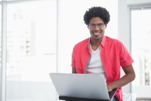 Casual businessman smiling and using laptop