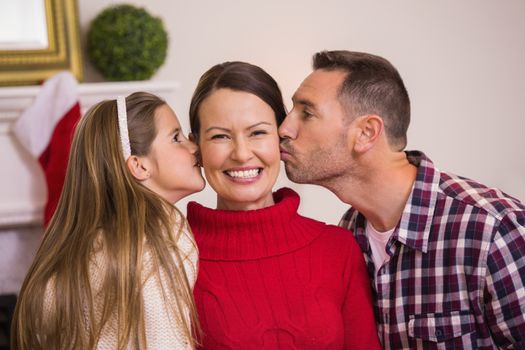 Daughter with her father kissing her mother at home in the living room