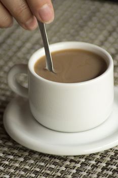 Hand stirring spoon in cup of coffee expresso